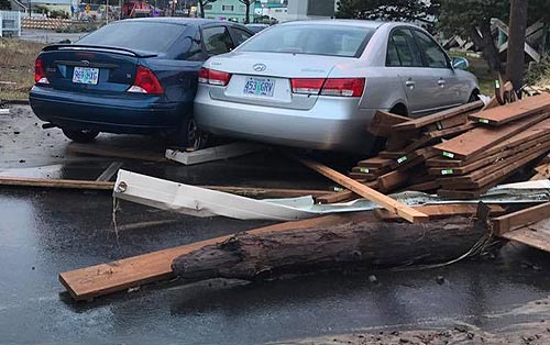 big waves and logs tossed onto a parking lot in Rockaway Beach squish cars together